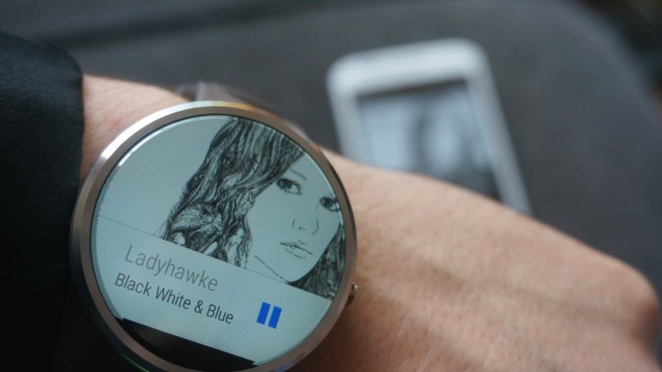 À frente, Moto 360. Atrás, smartphone onde a música está tocando.